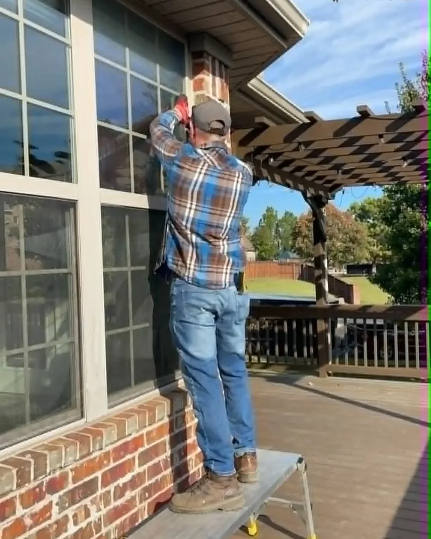 Working from a ladder on an exterior window above a deck