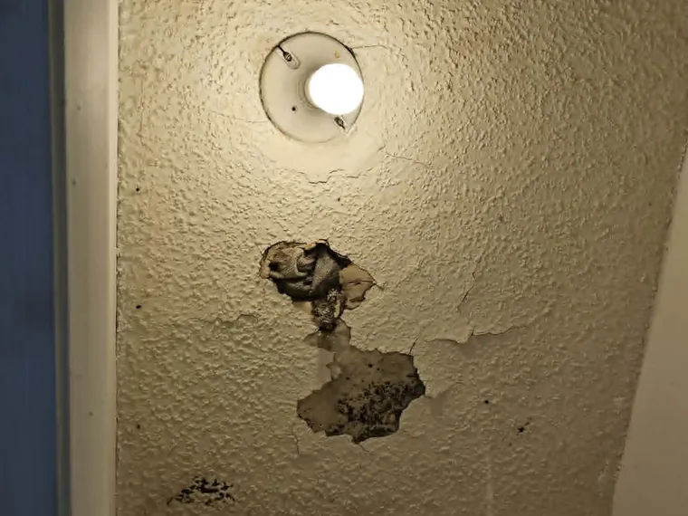 Damaged stucco around an exterior light fixture