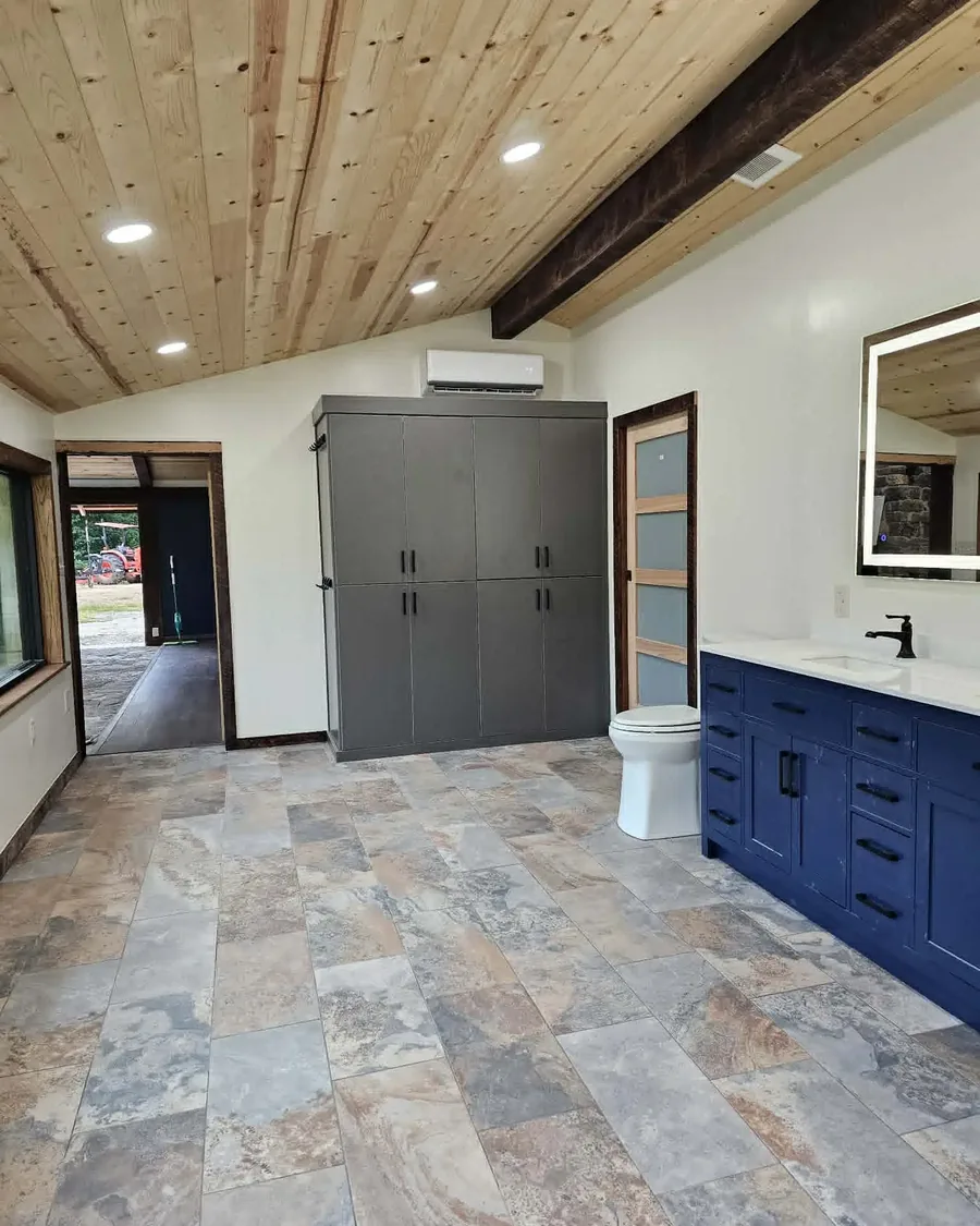 Finished bathroom with double vanity, wood ceiling and stone tile floor
