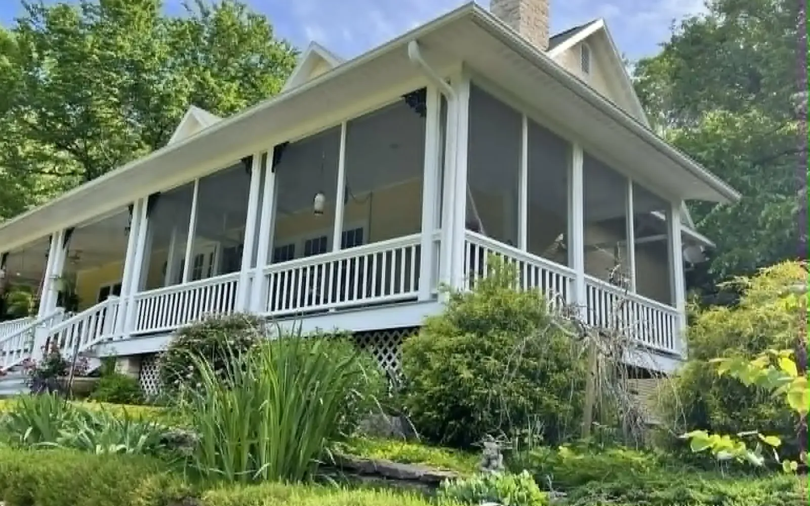 Large screened wraparound porch with white columns and railings on a Northwest Arkansas home